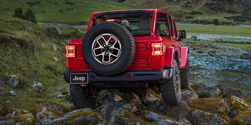 A red 2025 Jeep Wrangler driving through a river near Enumclaw, WA