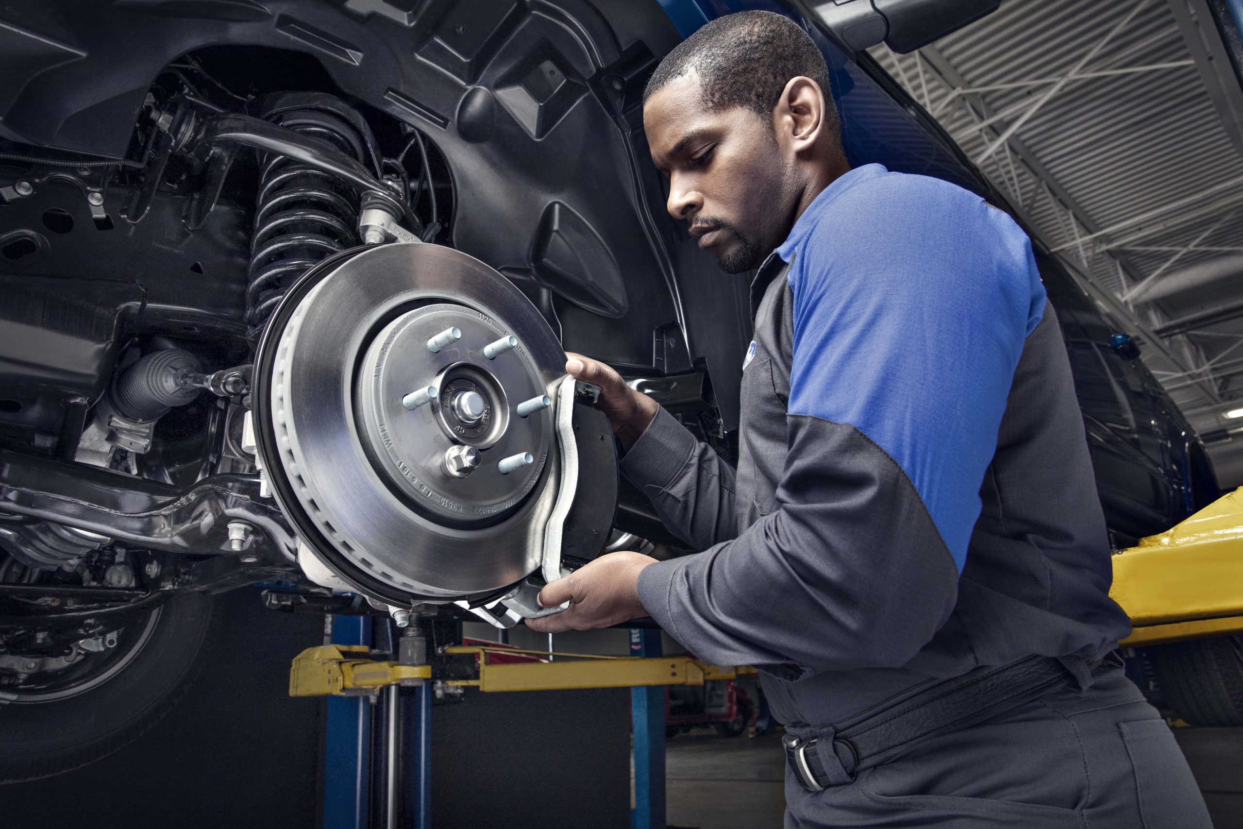 A mechanic working on the brake system of a vehicle, replacing the brake pads and inspecting the components.