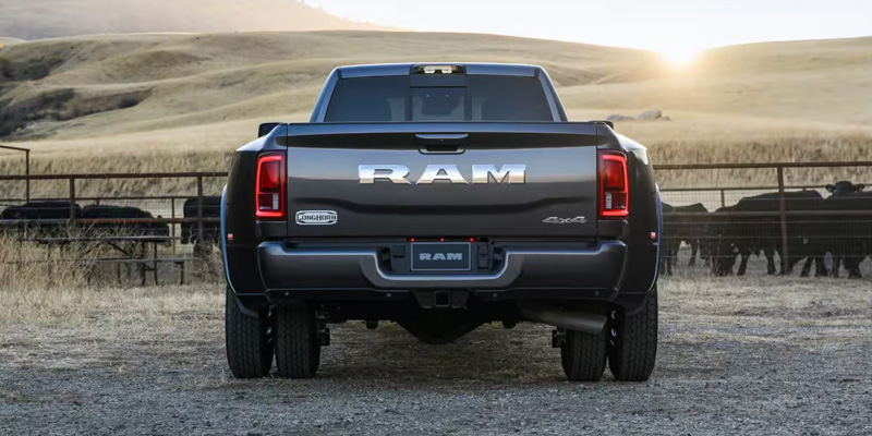 A rear view of a RAM 3500 pickup truck in a rural setting with cattle in the background.