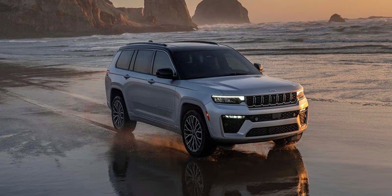 SUV driving along the beach during sunset.